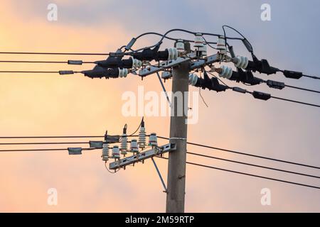 Hochspannungsleitungen auf dem elektrischen Pol bei Sonnenaufgang Stockfoto