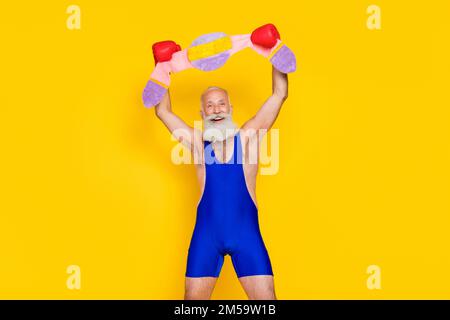 Foto: Begeistert aufgeregte Männerhände tragen Boxhandschuhe tragen Champion-Gürtel isoliert auf gelbem Hintergrund anheben Stockfoto
