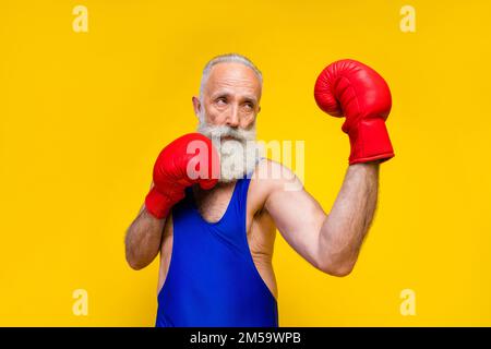 Foto einer fokussierten Person Tragen Sie Boxhandschuhe Stanzung isoliert auf gelbem Hintergrund Stockfoto