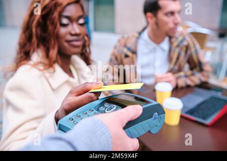 Nahaufnahme einer Frau, die kontaktlose Zahlungen mit einer Kreditkarte in einem Café tätigt. Stockfoto