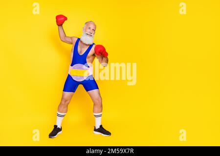 Großes Foto eines gutaussehenden Sportlers Boxhandschuhe tragen weicher, flauschiger Gürtel leerer Raum isoliert auf gelbem Hintergrund Stockfoto
