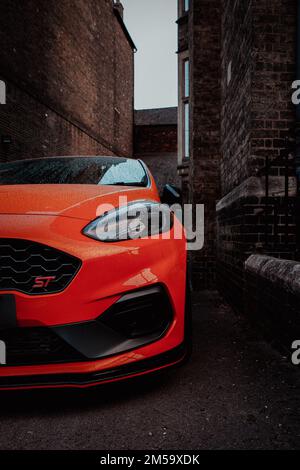 PETERBOROUGH, GROSSBRITANNIEN - 9. SEPTEMBER 2022. Nahaufnahme eines Ford Fiesta ST Sportwagens aus einem niedrigen Winkel in heißem Orange mit Karosserieausrüstung im Stil eines städtischen en Stockfoto