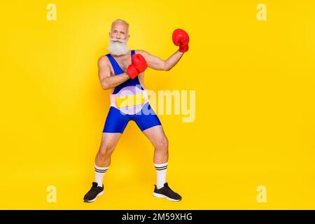 Ganzkörperporträt des erfolgreichen Großvaters Tragen Sie Boxhandschuhe Champion Gürtel isoliert auf gelbem Hintergrund Stockfoto