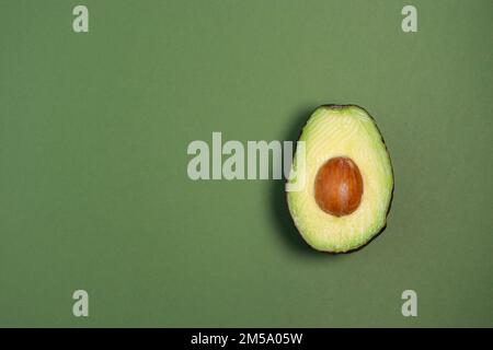 Nahaufnahme von frischer reifer Avocado auf grünem Hintergrund, Kopierbereich Stockfoto