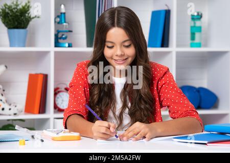 Schüler schreiben im Übungsbuch, studieren im Klassenzimmer. Glückliches Schulmädchen. Stockfoto