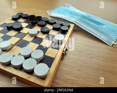 Schachbrett mit Schachbrettern - Business-Strategieplanung. Schachbrett aus Kunststoff auf einem braunen Holztisch. Covid-19-Pandemie Stockfoto