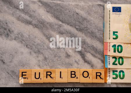 Word EURIBOR ist in Holzbuchstaben geschrieben, nahe an einem Teil der Euro-Banknoten 5, 10, 20 und 50. Stockfoto