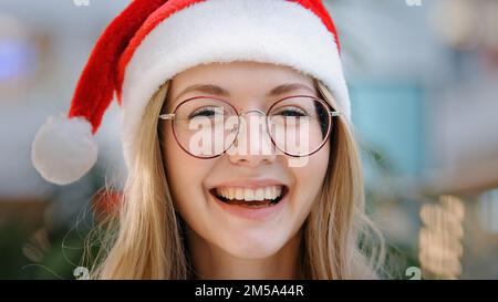Nahaufnahme Porträt lustig lächelnde Zahnothy lachend fröhliche weiße Frau Frau Frau Frau Frau Frau Frau Frau Frau mit Weihnachtsmann Weihnachtsmann Weihnachtsmütze und Brille schauen auf Kamera Lächeln Stockfoto