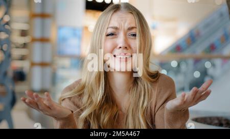 Verwirrte Weiße Frau verärgert wütende blonde Dame drinnen fragt, was passiert ist, Händchenhaltend vs. Unzufrieden vor der Kamera zu sehen, verwirrte wütend Stockfoto