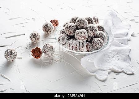 Köstliche Kokosnuss-Schokoladenbällchen mit geriebener Kokosnuss. Weiche, köstliche und flauschige Kokosnussbällchen mit Rum, Keksen und Schokolade Stockfoto