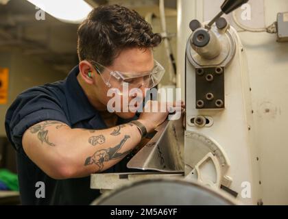 PHILIPPINE SEA (15. Februar 2022) Aviation Structural Mechanic Airman Daniel Garcia, aus Los Angeles, schmiedet eine Platte im Airframe Shop an Bord des Flugzeugträgers USS Abraham Lincoln (CVN 72) der Nimitz-Klasse. Die Abraham Lincoln Strike Group befindet sich in einem geplanten Einsatz im US-7.-Flottenbereich, um die Interoperabilität durch Allianzen und Partnerschaften zu verbessern und gleichzeitig als einsatzbereite Truppe zur Unterstützung einer freien und offenen Region Indo-Pacific zu fungieren. Stockfoto