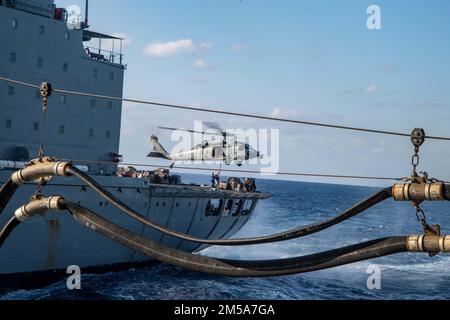 PHILIPPINE SEA (15. Februar 2022) ein MH-60s Sea Hawk Helikopter vom Helicopter Sea Combat Squadron (HSC) 25 führt eine vertikale Auffüllung mit dem Flottenauffüllöler USNS Yukon (T-AO 202) durch. Amerika, das führende Schiff der America Amphibious Ready Group, ist zusammen mit der 31. Marine Expeditionary Unit im Zuständigkeitsbereich der US-amerikanischen 7.-Flotte tätig, um die Interoperabilität mit Verbündeten und Partnern zu verbessern und als einsatzbereite Eingreiftruppe zur Verteidigung von Frieden und Stabilität in der Region Indo-Pazifik zu dienen. Stockfoto