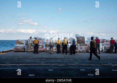 SEELEUTE DER PHILIPPINEN SEE (15. Februar 2022), die dem nach vorn verlegten Amphibienschiff USS America (LHA 6) zugeteilt sind, transportieren während einer Wiederauffüllung mit dem Flottenöler USNS Yukon (T-AO 202) Fracht. Amerika, das führende Schiff der America Amphibious Ready Group, ist zusammen mit der 31. Marine Expeditionary Unit im Zuständigkeitsbereich der US-amerikanischen 7.-Flotte tätig, um die Interoperabilität mit Verbündeten und Partnern zu verbessern und als einsatzbereite Eingreiftruppe zur Verteidigung von Frieden und Stabilität in der Region Indo-Pazifik zu dienen. Stockfoto