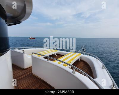 Kreuzfahrtschiff elegante Sonnenliege mit gelber Streifenband auf dem Bootsdeck mit Blick auf die Landschaft auf dem Mittelmeer, Europa Sommerurlaub. Stockfoto