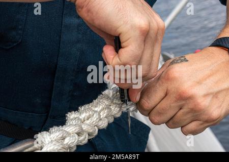 220215-N-FA490-1356 MANILA, Philippinen (15. Februar 2022) – Boatswain's Mate 2. Klasse Patrick Hix, aus Independence, Missouri, schneidet die ausgefransten Kanten an einer Rettungslinie auf dem Cockpit des Küstenschiffes USS Jackson (LCS 6) der Independence-Variant. Am Destroyer-Geschwader (DESRON) 7 beteiligt, befindet sich Jackson im Rotationseinsatz im US-7.-Flottengebiet, um die Sicherheit und Stabilität in der Region zu unterstützen. Und mit den alliierten und Partnerschifffahrtsleuten zusammenzuarbeiten, um die Sicherheit und Stabilität des Seeverkehrs zu gewährleisten, die Grundpfeiler eines freien und offenen Indopazifiks. Stockfoto