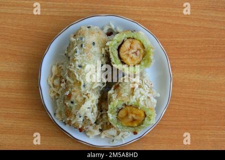 Zerkleinerter und frittierter, unreifer Reis und geriebene Kokosnuss-Bananenrollen Stockfoto