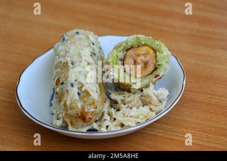 Zerkleinerter und frittierter, unreifer Reis und geriebene Kokosnuss-Bananenrollen Stockfoto