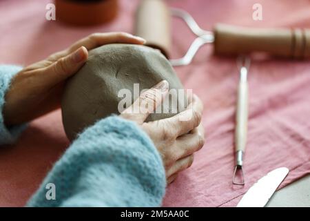 Weibliche Töpferkünstlerin bereitet Ton zum Formen vor. Nahaufnahme von Frauenhänden mit Ton. Kreative Handarbeit. Keramikstudio. Stockfoto