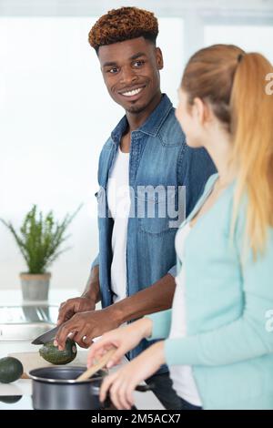 Gemischtes Paar, das zusammen in der Küche das Abendessen zubereitet Stockfoto