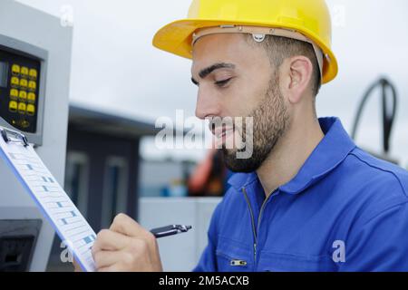 Männlicher Techniker schreibt auf Zwischenablage Stockfoto