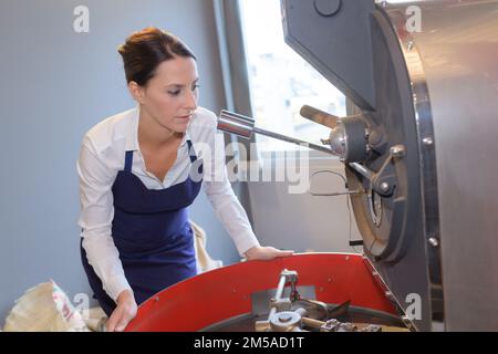 Weibliche Mitarbeiterin, die eine industrielle Mischmaschine bedient Stockfoto