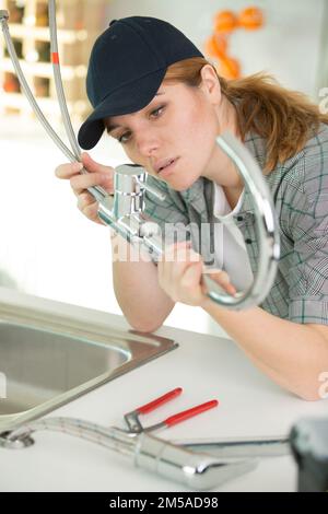 Eine Klempnerin, die einen neuen Küchenhahn installiert Stockfoto