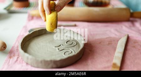 Nahaufnahme: Weibliche Hände arbeiten mit Clay Makes Future Ceramic Plate, Kurse des Handbaus in Modern Pottery Workshop, Creative People Stockfoto