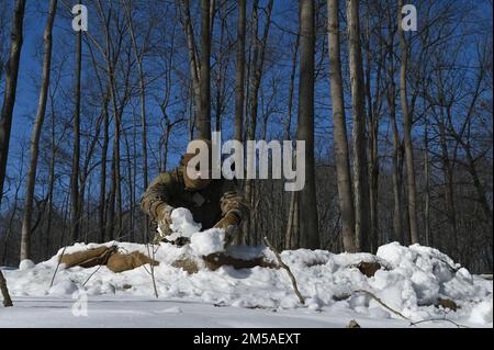 Staff Sgt. David Greenwood, ein Verteidiger, der dem 926. Sicherheitsgeschwader am Nellis Air Force Base, Nevada, zugeteilt ist, packt während einer statischen Verteidigungsübung im Camp James A. Garfield Joint Military Training Center, Ohio, am 15. Februar 2022 Schnee, um die Sandsäcke um seine Position zu tarnen. Die Übung war Teil des Integrated Defense Leadership Kurses, einer intensiven, zweiwöchigen, praxisorientierten Lernerfahrung, die Reserve Defenders helfen soll, Kampfbereitschaft zu erreichen und aufrechtzuerhalten. (USA Air Force Photo/Staff Sgt. Noah Tancer) Stockfoto