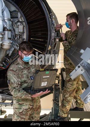 Royal Air Force Senior Aircraftman Technician Joseph Eastham liest technische Bestellungen von einem Laptop als RAF CPL. Ben Archer entfernt einen Bolzen von einem C-17-Triebwerktrainer auf dem Luftwaffenstützpunkt Dover, Delaware, 15. Februar 2022. Eastham und Archer, beide C-17 Globemaster Wartungsarbeiter von 99 Squadron, RAF Brize Norton, Großbritannien, nahmen an dem 64-stündigen C-17-Kurs zum Motorwechsel Teil, in dem sie gelernt haben, wie der Pratt & Whitney F117-PW-100 Turbofan-Motor sicher aus- und wieder eingebaut wird. Stockfoto