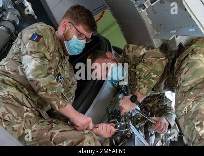 Joseph Eastham, Senior Aircraftman Technician der Royal Air Force, hält einen Schraubenschlüssel als RAF CPL. Ben Archer löst einen Bolzen von einem C-17-Triebwerkstrainer auf dem Luftwaffenstützpunkt Dover, Delaware, 15. Februar 2022. Eastham und Archer, beide C-17 Globemaster Wartungsarbeiter von 99 Squadron, RAF Brize Norton, Großbritannien, nahmen an dem 64-stündigen C-17-Kurs zum Motorwechsel Teil, in dem sie gelernt haben, wie der Pratt & Whitney F117-PW-100 Turbofan-Motor sicher aus- und wieder eingebaut wird. Stockfoto