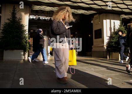 London, Großbritannien. 26. Dezember 2022. Eine Frau schaut auf ihr Handy vor dem Selfridges-Laden in der Oxford Street im Zentrum von London. (Kreditbild: © Dinendra Haria/SOPA Bilder über ZUMA Press Wire) Stockfoto