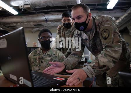 USA Armeecpt. Nathaniel Perry, Left, ein Offizier der Artillerie und Sergeant Jimmy Nguyen, Middle, ein Spezialist für Signaloperationen, beide dem amerikanischen First Corps und den USA zugewiesen Air Force Staff Sgt. Matthew Joblin, Right, ein Joint Communications Technician, der dem Joint Communications Support Element zugeteilt ist, hat am 16. Februar 2022 eine Kommunikationsleitung auf der USNS-Stadt Bismarck auf der Marinebasis Guam eingerichtet. Die Dienstmitarbeiter testen Kommunikationsfähigkeiten, um die Einsatzbereitschaft zu verbessern, die gemeinsame Interoperabilität zu demonstrieren und im Pazifikraum verteilte Missionsbefehle auszuüben. Stockfoto