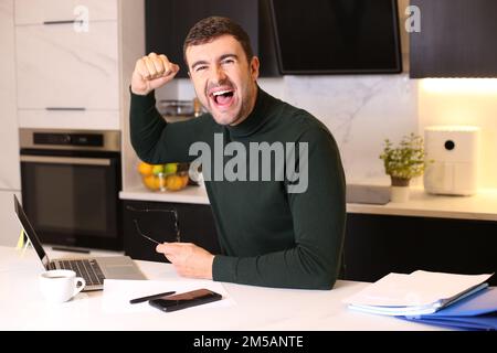 Ein Mann, der einen Sieg vom Heimbüro aus feiert Stockfoto