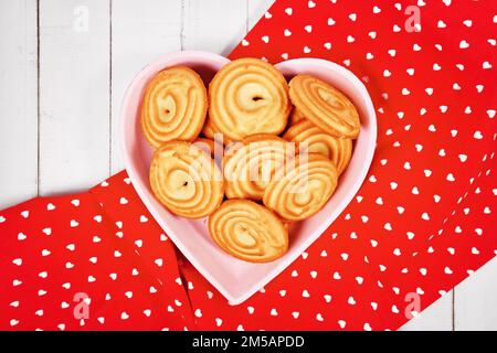 Herzförmige Platte mit runden ringförmigen Spritz-Keksen namens Spritzgeback, eine Art deutscher Butterkekse Stockfoto