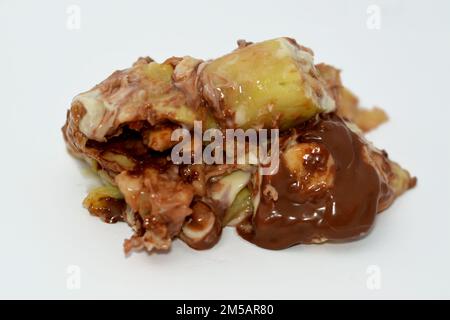 Süße Schokoladenmischrollen gefüllt mit Bananenobststücken, Nüssen, Haselnüssen, Rosinen, weißer und brauner Schokoladensoße mit weißen und dunklen Garnierungen Stockfoto