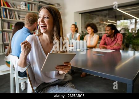 Lächelnd treffen sich verschiedene Kollegen in einem Brainstorming in der Vorstandsetage, um gemeinsam Finanzstatistiken zu diskutieren Stockfoto