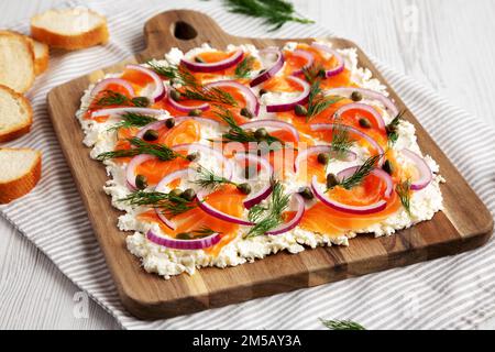 Hausgemachtes Bagel-Brett aus Frischkäse-Lachs mit weißem Holzhintergrund, Seitenansicht. Stockfoto