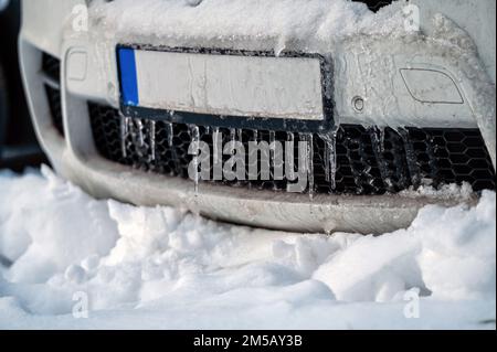 Vorderer Stoßfänger in Eiszapfen im Winter. Eingefrorener Autostoßfänger mit Eiszapfen. Stockfoto