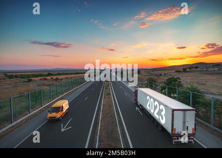 Fahren Sie auf offener Straße bei schönem Sonnenuntergang in Richtung Neujahr 2023. Logistik- und Transportindustrie auf der Autobahn. Stockfoto