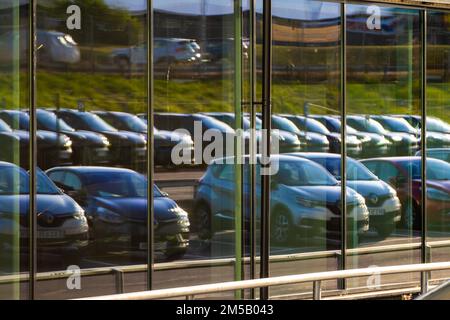 Göteborg, Schweden - Juli 30 2022: Lange Pkw-Reihen in einem Autohaus, die in einer Glasfassade verspiegelt sind Stockfoto