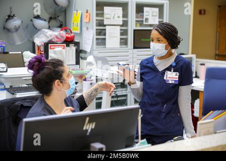 BROCKTON, Mass. – USA Air Force Capt. Suzie Guzman, eine registrierte Krankenschwester, die den USA zugeteilt ist Militärmedizinisches Team der Luftwaffe, das in Brockton, Massachusetts, stationiert ist, diskutiert die Patientenversorgung mit Shannon Sherman, Left, einer registrierten Krankenschwester am Signature Healthcare Brockton Hospital, im Rahmen der COVID-Response-Operationen, Feb. 17, 2022, USA Nördliches Kommando, durch die USA Army North ist nach wie vor entschlossen, das Verteidigungsministerium flexibel bei der COVID-Reaktion der gesamten Regierung zu unterstützen. Stockfoto