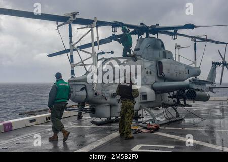 PHILIPPINE SEA (17. Februar 2022) Marines, die der 31. Marine Expeditionary Unit (MEU) zugeteilt sind, bereiten sich darauf vor, einen AH-1Z Cobra-Hubschrauber vom Marine Medium Tiltrotor Squadron (VMM) 265 auf das Cockpit des Amphibienschiffs USS Green Bay (LPD 20) zu verlegen. Green Bay, Teil der Expeditionary Strike Group 7, ist zusammen mit der 31. MEU im Zuständigkeitsbereich der US-amerikanischen 7.-Flotte tätig, um die Interoperabilität mit Verbündeten und Partnern zu verbessern und als einsatzbereite Eingreiftruppe zur Verteidigung von Frieden und Stabilität in der Region Indopazifik zu dienen. Stockfoto