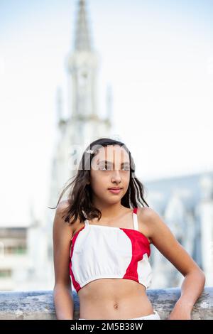 Wunderschönes Touristenmädchen an der Ortiz-Brücke mit La Ermita-Kirche im Hintergrund in der Stadt Cali in Kolumbien Stockfoto