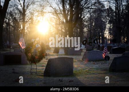 Die Sonne geht auf amerikanischen Flaggen und Weihnachtskränzen auf einem Friedhof in Wisconsin auf. Stockfoto