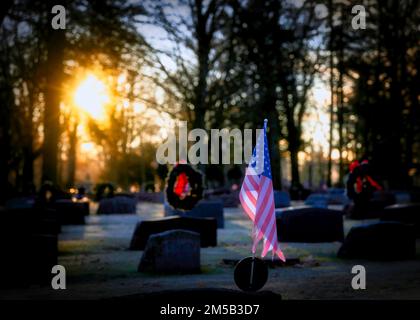 Die Sonne geht auf amerikanischen Flaggen und Weihnachtskränzen auf einem Friedhof in Wisconsin auf. Stockfoto