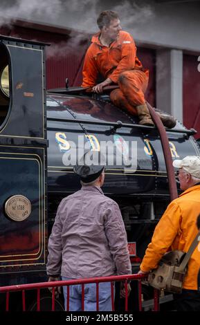 Mechaniker reparieren eine alte Dampflokomotive in einem Depot Stockfoto