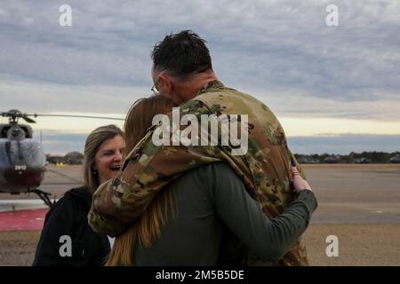 Chief Warrant Officer Eitel Ben Hahn, Lakota Helicopter Instructor Pilot für Delta Company 1. Battalion 223. Aviation Regiment, umarmt seine Tochter Grace als seine Frau Beth, Schaut nach seinem letzten Flug im Shell Army Heliport, Fort Rucker, Alabama, am 18. Februar 2022. Im Jahr 1990 schloss sich Hahn dem Aufruf für aktive Einsätze bei der Operation Desert Shield und Desert Storm an. Stockfoto