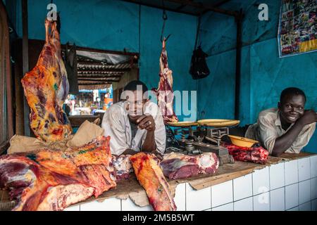 Zwei fröhliche einheimische Metzger , die Fleisch auf dem Markt verkaufen , Bamako , Mali , Westafrika . Stockfoto