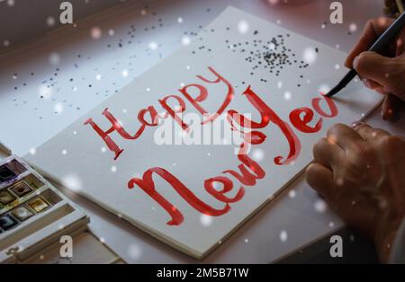 DIY-Inschrift Happy New Year mit roter Farbe, Pinsel auf Papier Weihnachtspostkarte Stockfoto