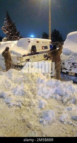 Buffalo, New York, USA. 26. Dezember 2022. Soldaten der New York Army National Guard, die der 827. Engineer Company und dem 174. Attack Wing zugeteilt wurden, helfen bei der Schneeräumung, um einen AMR-Krankenwagen als Teil der Reaktion der New York National Guard auf einen großen Schneesturm zu Bergen. Die Nationalgarde von New York entsandte 433 Soldaten nach dem Schneesturm, der die Region über das Weihnachtswochenende heimsuchte. (Bild: © Eric Durr/New York National Guard/ZUMA Press Wire) Stockfoto